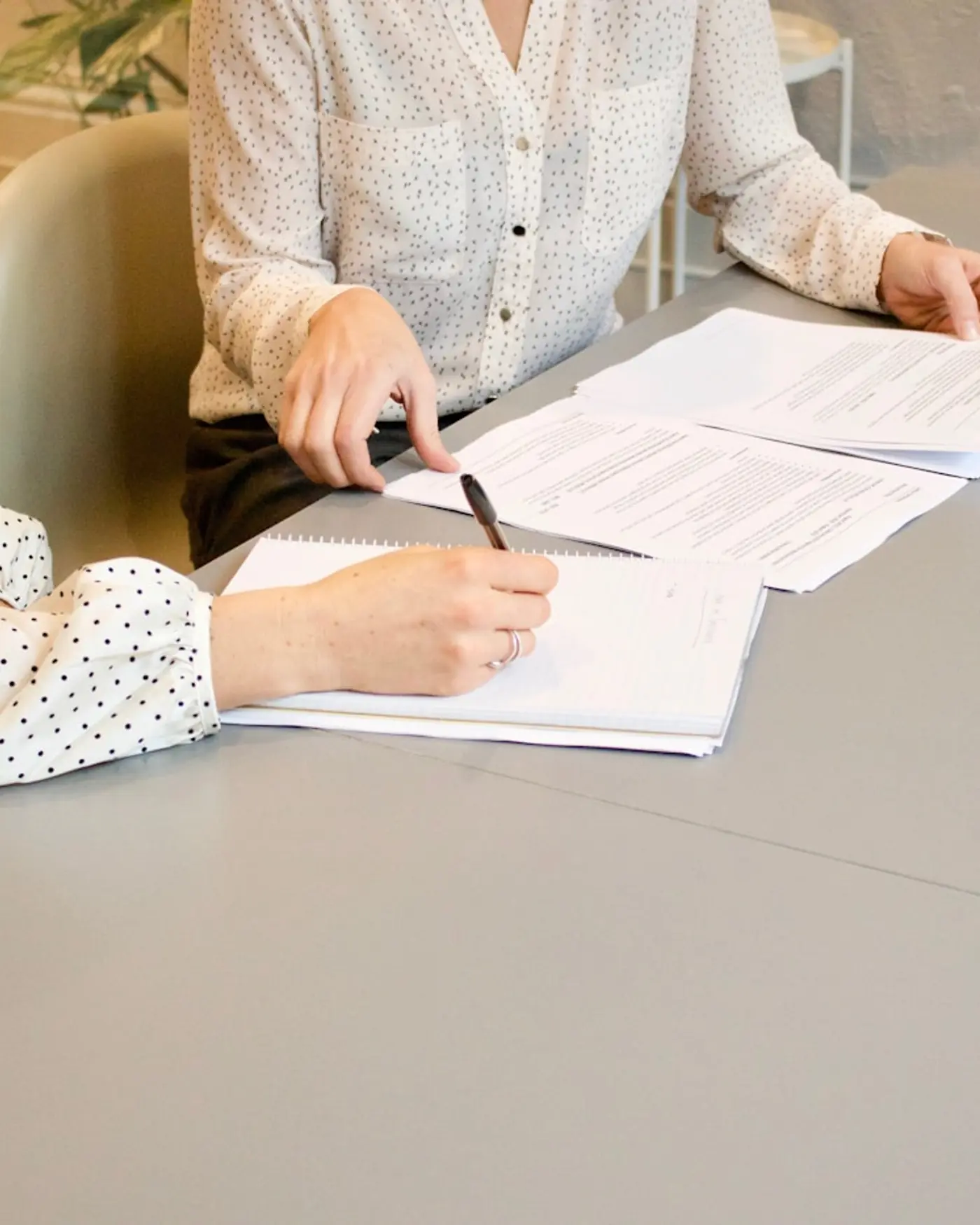 Persona firmando un documento con otra al lado siguiendo el texto