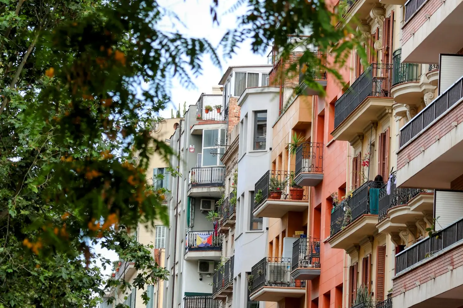 Fachadas de edificios de viviendas con balcones de forja y árboles delante
